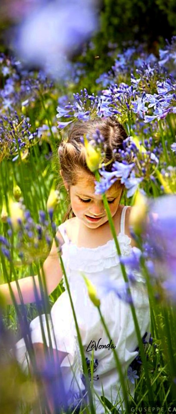 маленькая девочка нюхает цветы